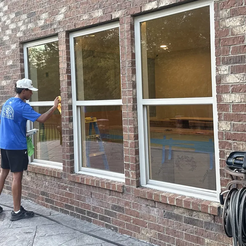 Lucent technician hand-detailing exterior windows on a brick home