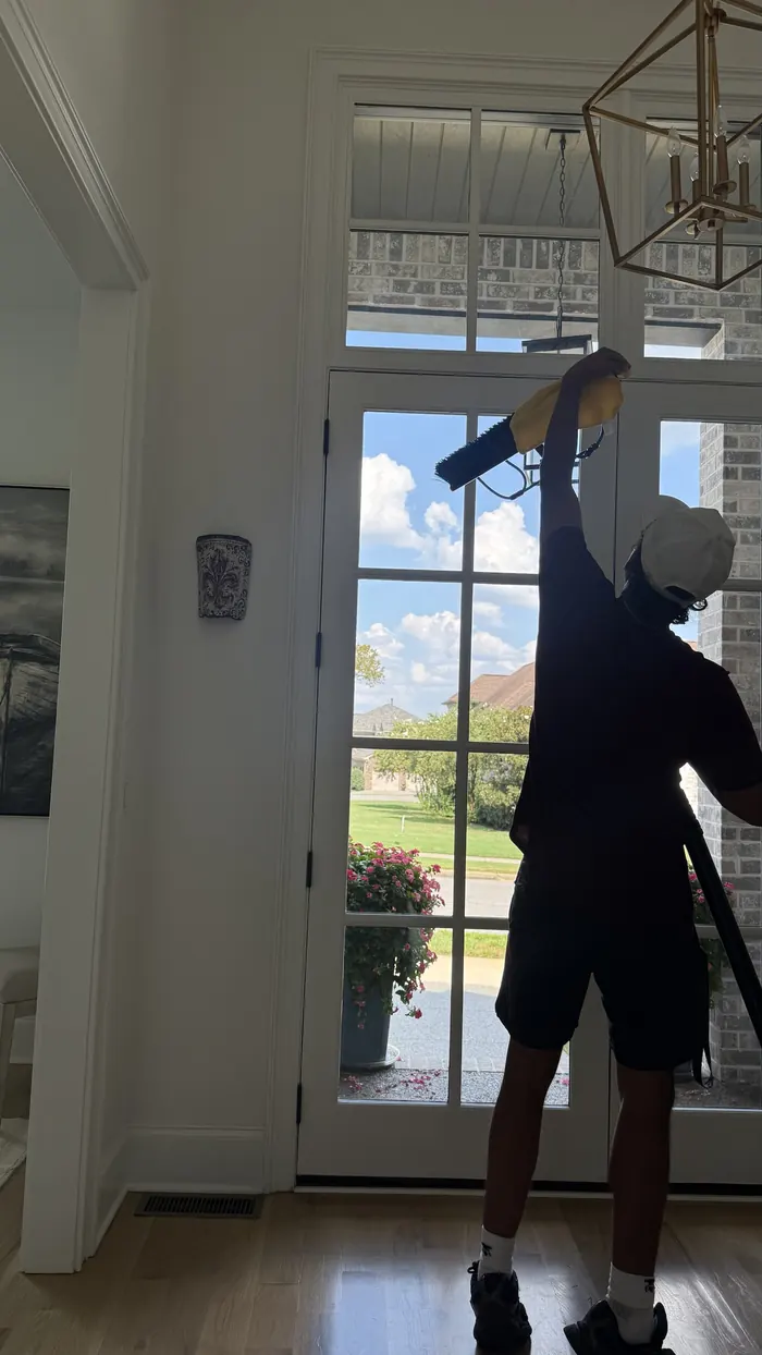 Lucent technician cleaning a high interior transom window
