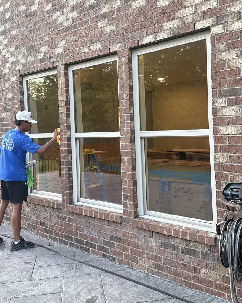 Lucent Exteriors crew member hand-cleaning windows on a brick home