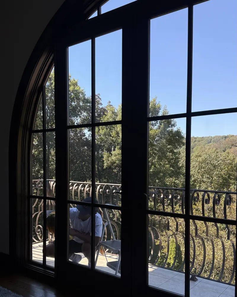 View through freshly cleaned arched windows and frames to a balcony and wooded hillside